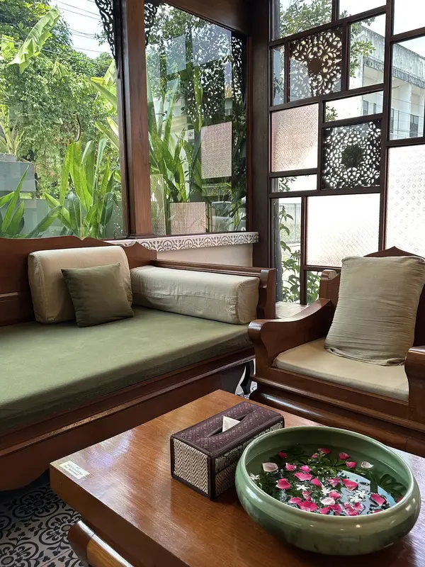 Lounge with teak daybed, green cushions and a bowl of floating petals