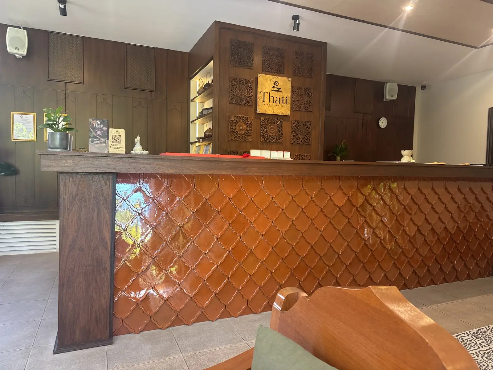 Reception desk with a terracotta scale-tile front and carved teak panels