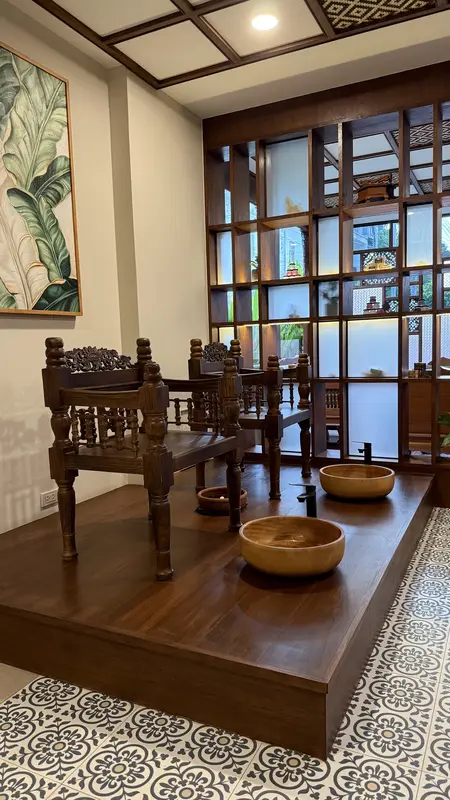 Teak chairs and wooden foot-wash bowls on a raised platform, with lattice shelves behind